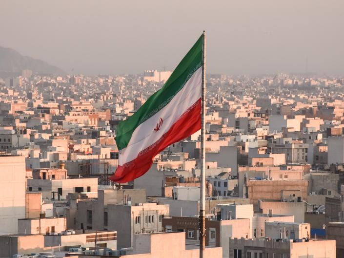 Иранский флаг развевается на фоне городского пейзажа в Тегеране, Иран