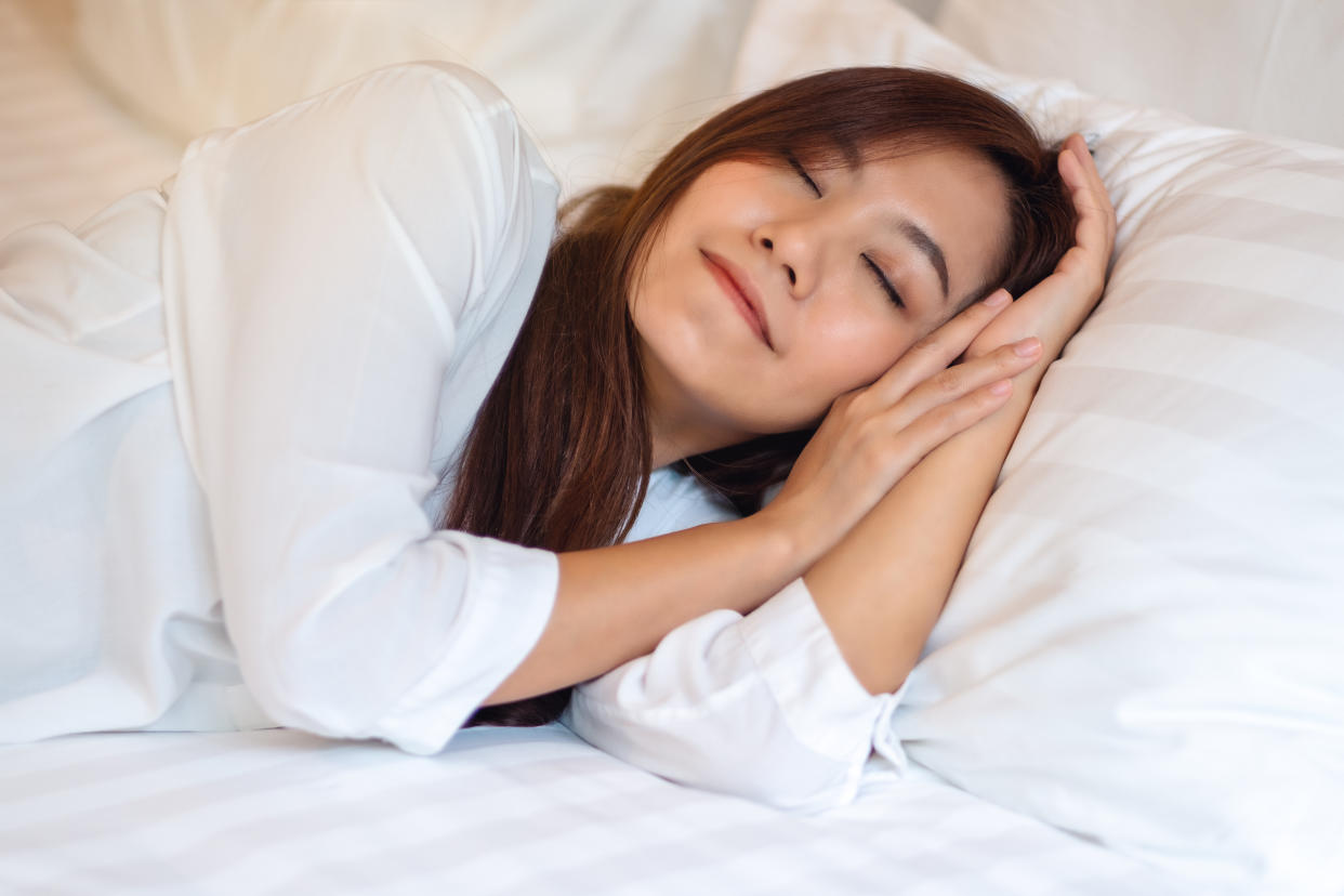 A beautiful asian woman sleeping in a white cozy bed at home