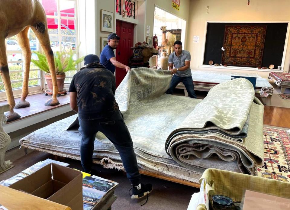 Employees flip through dozens of rugs in the showroom to carefully extract the perfect one for a customer to take home.