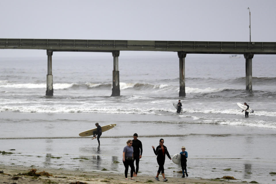 Surfers get out of the water near the Ocean Beach pier Thursday, April 30, 2020, in San Diego. A memo sent to California's police chiefs says Gov. Gavin Newsom intends to close all beaches and state parks starting Friday in the wake of a weekend that saw a crush of people at open seashores. (AP Photo/Gregory Bull)