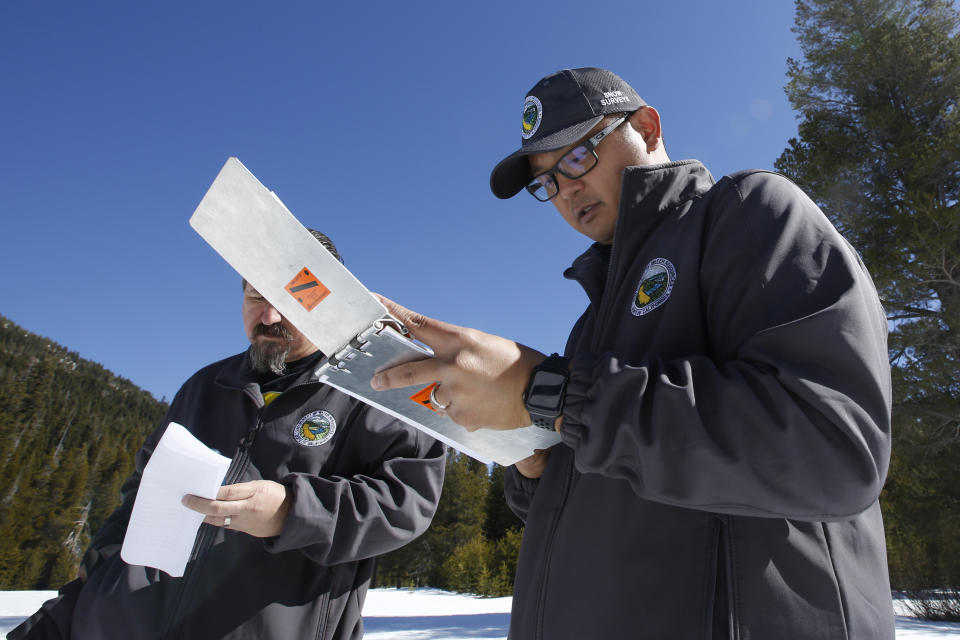 Sean de Guzman, chief of snow surveys for the California Department of Water Resources, accompanied by DWR's Chris Orrock, left, goes over the final numbers after conducting the third snow survey of the season at Phillips Station near Echo Summit, Calif., Thursday, Feb. 27, 2020. The survey found the snowpack at 29 inches deep with a water content of 11.5 inches at this location. February is shaping up to be the driest on record for much of the state. (AP Photo/Rich Pedroncelli)