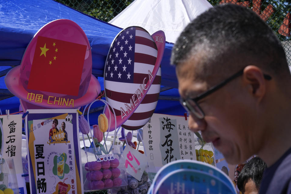 A man walks by a booth selling foods and beverages displaying planets shaped of China and American flags during a Spring Carnival in Beijing on May 13, 2023. Hong Kong's leader on Tuesday, May 16 said the sentencing on spying charges of a U.S. citizen in China, who was also a permanent resident of the semi-autonomous city, illustrated that the territory should "stay vigilant to national security risks hidden in society." (AP Photo/Andy Wong)