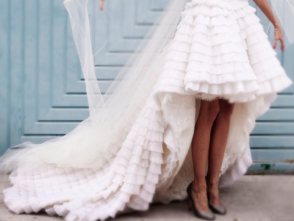 bride in a high-low dress fixing her veil