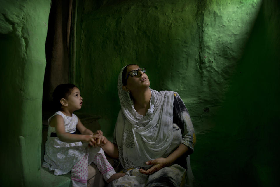 In this Sept. 27, 2019, photo, Sumaira Bilal, wife of Kashmiri detainee Bilal Ahmed, talks to her two-year-old daughter as they sit for photographs on a staircase of their house in Srinagar, Indian controlled Kashmir. Ahmed was detained on the night of Aug. 5, the day Indian Prime Minister Narendra Modi’s Hindu-nationalist government repealed Article 370 of the Indian Constitution, stripping Kashmir of its statehood. Sumaira says her daughter points to the window often and calls for her father “Baba, Baba, when are you coming back?” (AP Photo/ Dar Yasin)
