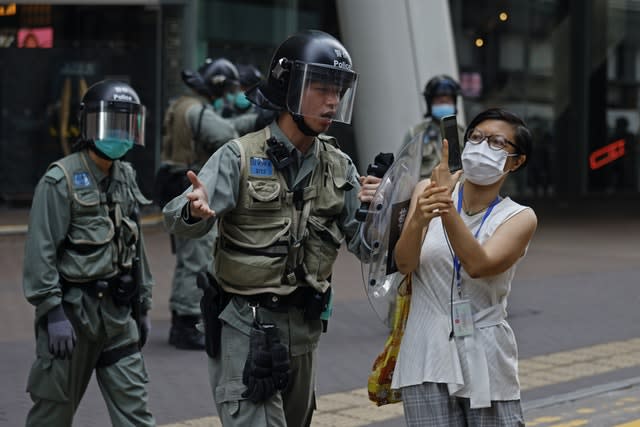 Riot policeman pushes a woman as she is taking a photograph of detained protesters in Mongkok, Hong Kong 