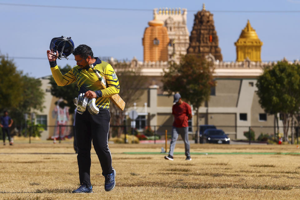 Pavan Kumar Machiraju walks off the field after batting during a cricket match between the Dallas Cricket Connections and the Kingswood Cricket Club, as the Karya Siddhi Hanuman Temple is seen in the background, in Frisco, Texas, Saturday, Oct. 22, 2022. (AP Photo/Andy Jacobsohn)