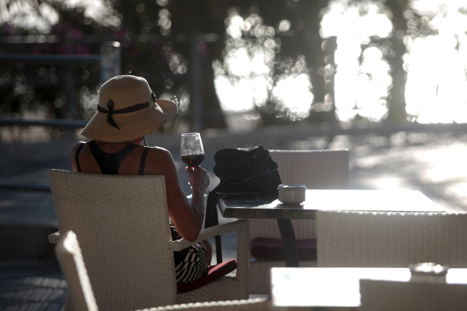 A woman sits in a terrace bar near the beach of Palma de Mallorca, Spain, Monday, June 15, 2020. Borders opened up across Europe on Monday after three months of coronavirus closures that began chaotically in March. (AP Photo/Joan Mateu)