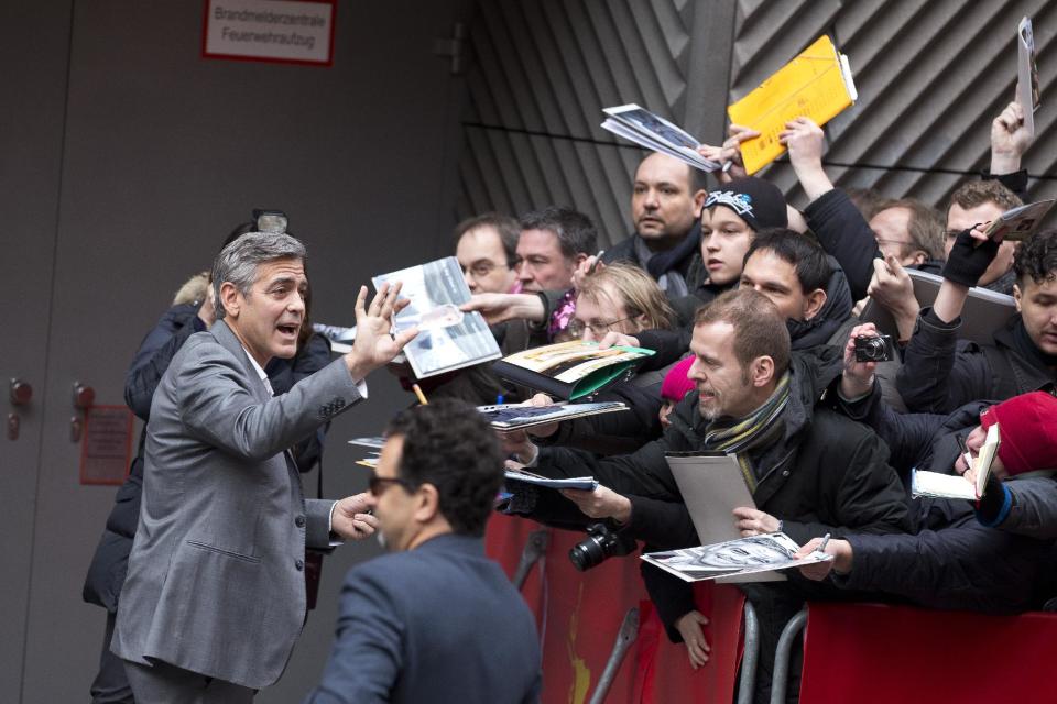 Actor George Clooney waves to fans as he arrives for photo call of the film The Monuments Men during the International Film Festival Berlinale, in Berlin, Saturday, Feb. 8, 2014. (AP Photo/Axel Schmidt)