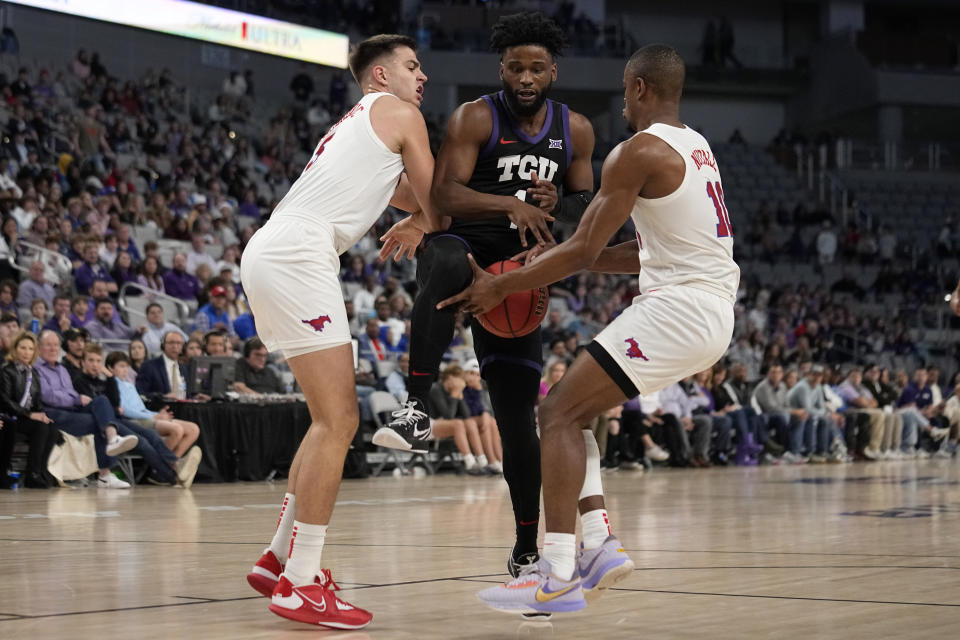 TCU guard Mike Miles Jr., center, has the ball stripped by SMU's Zach Nutall, right, during the first half of an NCAA college basketball game, Saturday, Dec. 10, 2022, in Fort Worth, Texas. At left is SMU's Stefan Todorovic. (AP Photo/Tony Gutierrez)