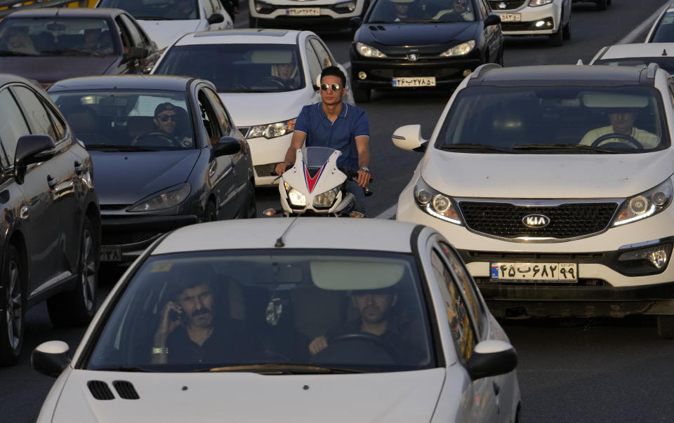 A man rides his motorcycle among cars in an afternoon traffic jam in northern Tehran, Iran, Tuesday, July 2, 2024. Comments suggesting that Iran's reformist presidential candidate could increase government-set gasoline prices have raised fears of a repeat of nationwide protests. (AP Photo/Vahid Salemi)