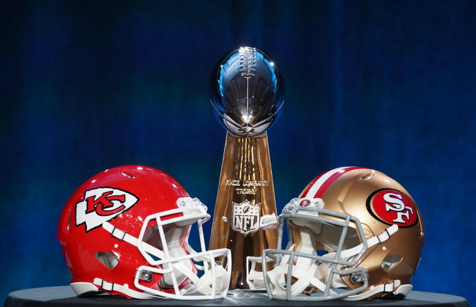 The Vince Lombardi Trophy sits between the helmets of the Kansas City Chiefs and San Francisco 49ers, who also met in Super Bowl 54.