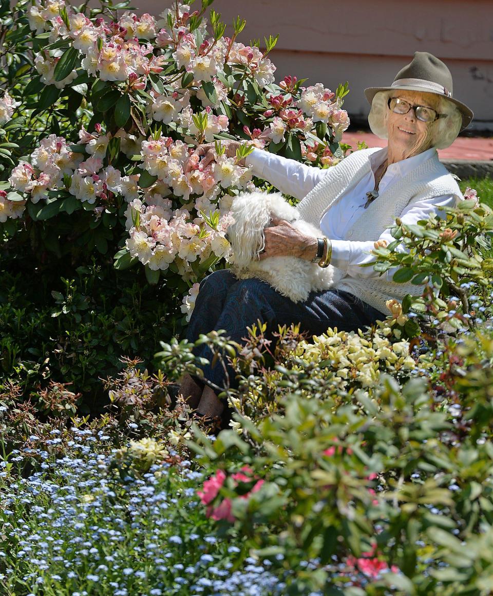 Blossom McBrier is shown with her dog Jamie sitting among some of the blooming plants and flowers in the 12-acre garden at her Fairview Township home in this 2018 file photo. The property, located at 6721 Brier Hill Road, is currently for sale.