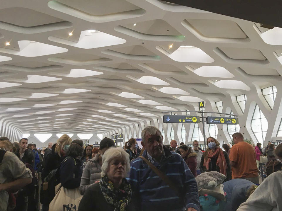 Passengers line up to board one of the few flights out of Morocco, in Marrakech, Thursday, March 19, 2020. Morocco suspended all international passenger flights and passengers ships to and from its territory last Sunday. Since then, citizens from all over the world found themselves stuck in the touristic country. (AP Photo/Elijah McKee)