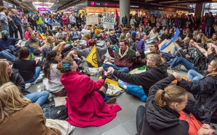 Des militants tiennent des pancartes lors d'un sit-in non violent sur le centre commercial de l'aéroport de Schiphol - Charles M Vella/SOPA Images/Shutterstock