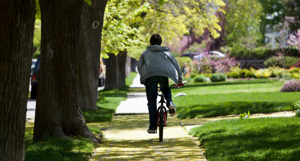 Stock image of a boy riding a bike without a helmet.