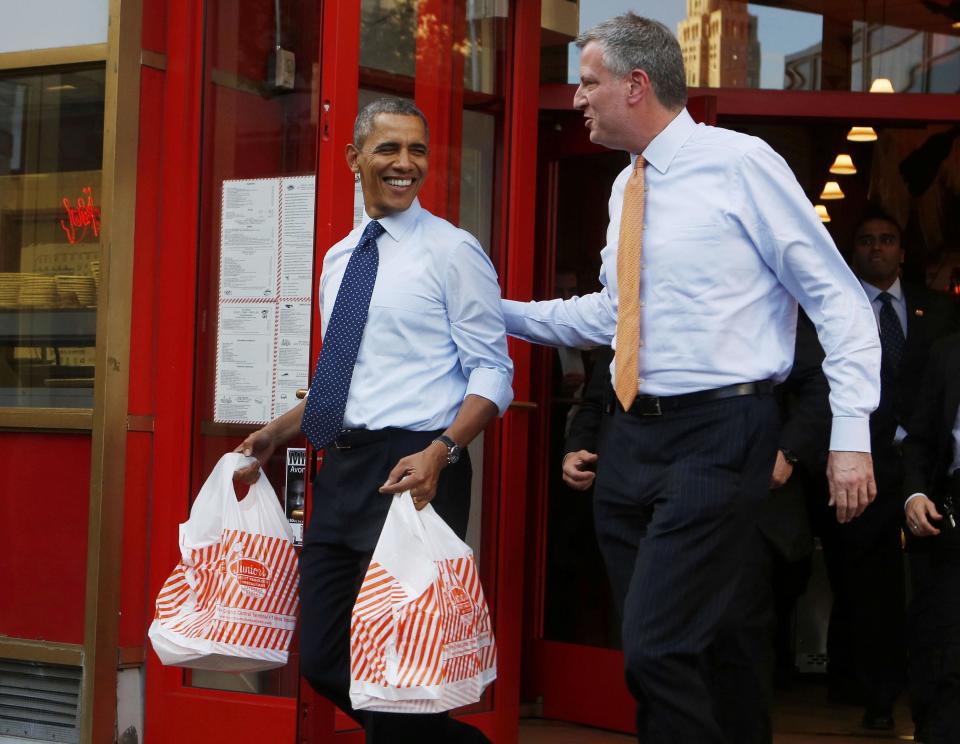 U.S. President Barack Obama walks out with two bags of cheesecake from Junior's Restaurant next to Democratic Mayoral candidate Bill de Blasio in Brooklyn, October 25, 2013. REUTERS/Larry Downing (UNITED STATES - Tags: POLITICS FOOD)