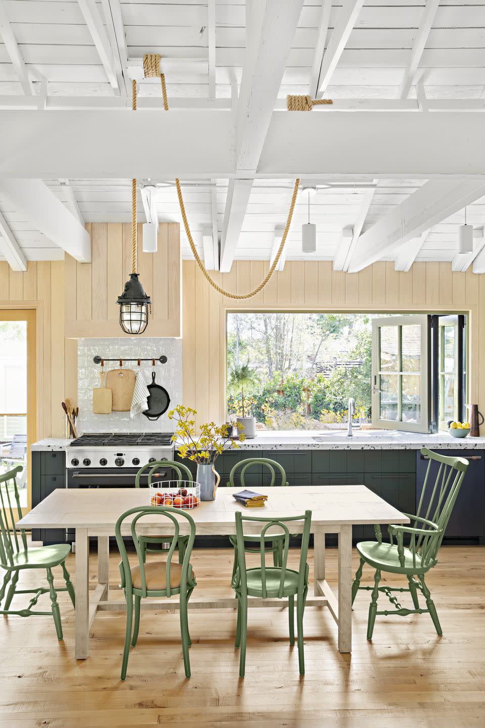 a kitchen with dark green lower cabinets and a table with green chairs in a lighter shade of green