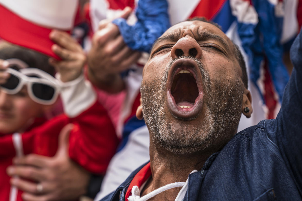 Mid-shot of euphoric Englishman shouting and celebrating after England national team scores goal during international game in crowded stadium