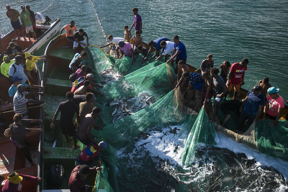 Pescadoras y pescadores sacan una red llena de peces frente a la costa de Chuao, Venezuela, el miércoles 7 de junio de 2023. Muchas de las mujeres perdieron sus trabajos debido a que la prolongada crisis del país acabó con el turismo en la zona y la pandemia de coronavirus empeoró su calidad de vida. (AP Foto/Matias Delacroix)