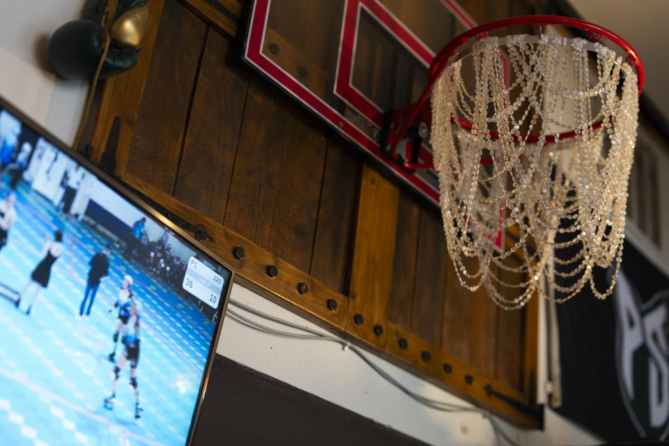 A roller derby match is played on a TV next to a decorated basketball hoop at The Sports Bra sports bar on Thursday, April 25, 2024, in Portland, Ore. (AP Photo/Jenny Kane)