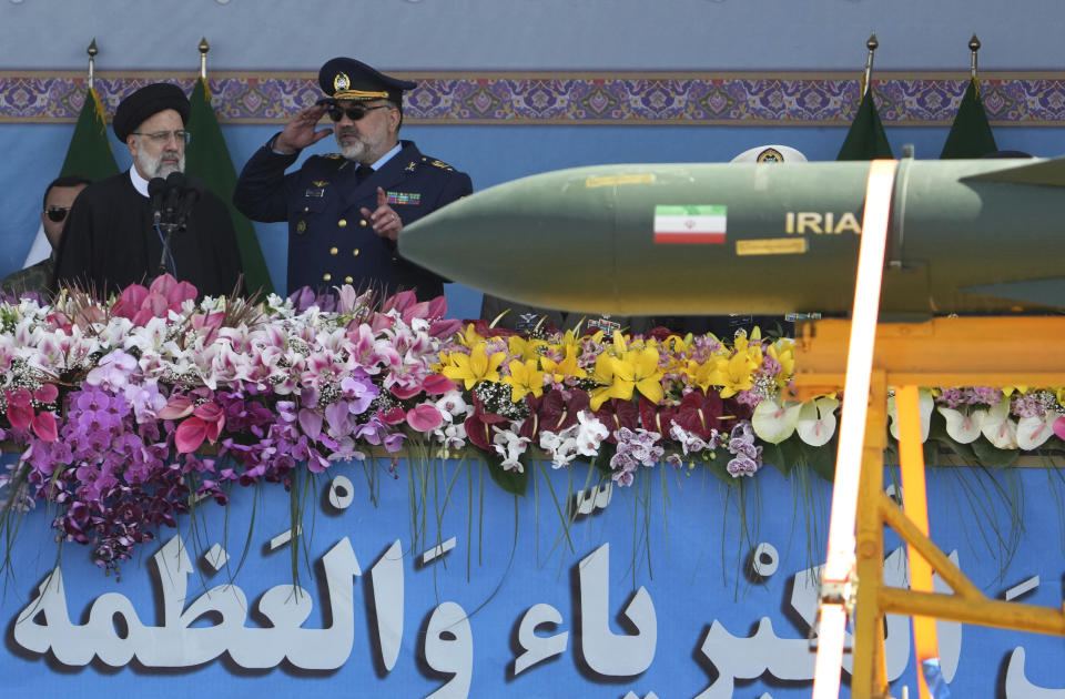 Iranian President Ebrahim Raisi, left, listens to the army's air force commander Gen. Hamid Vahedi as he reviews an army parade commemorating Army Day while a missile is carried on a truck in front of the mausoleum of the late revolutionary founder Ayatollah Khomeini just outside Tehran, Iran, Tuesday, April 18, 2023. President Raisi reiterated threats against Israel while though he stayed away from criticizing Saudi Arabia as Tehran seeks a détente with the kingdom. (AP Photo/Vahid Salemi)