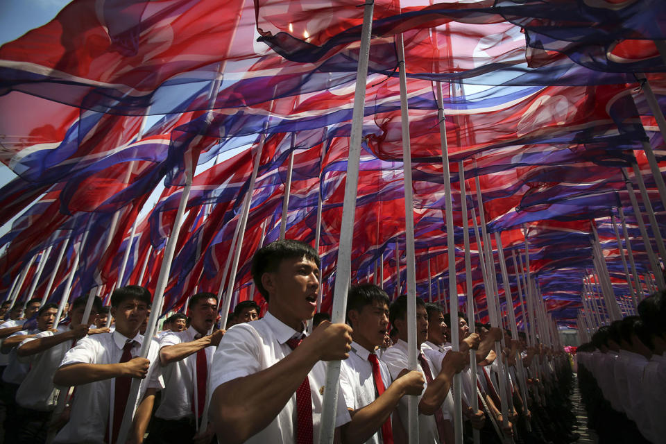 <p>Parade participants carry North Korean flags, July 27, 2013 during a mass military parade celebrating the 60th anniversary of the Korean War armistice in Pyongyang, North Korea. (Photo: Wong Maye-E/AP) </p>