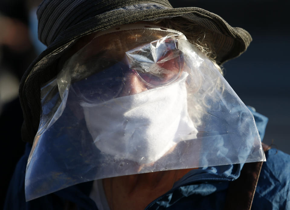 A woman wearing a homemade visor against the spread of the new coronavirus attends a protest during the curfew in front of the Serbian parliament building in Belgrade, Serbia, Thursday, April 30, 2020. Serbian opposition leaders gathered during an evening curfew to protest measures imposed by the populist authorities against the spread of the new coronavirus. Serbia's populist government in mid-March introduced some of the harshest measures in Europe, banning people over 65 years old from leaving their homes and imposing a daily and weekend curfews. (AP Photo/Darko Vojinovic)