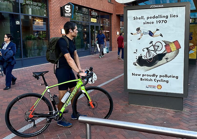 A cyclist looks at one of the satirical adverts in Reading, UK. 