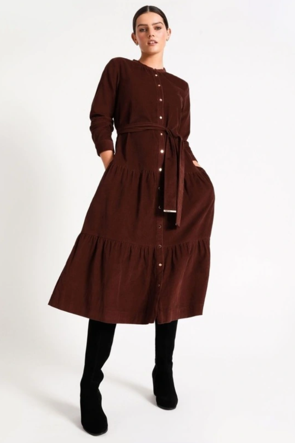 A model wears a dark red dress with long sleeves and button front and a frilled tiered hem over black boots.