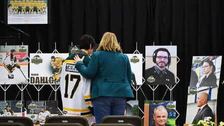 Mourners comfort each other as they look at photographs before a vigil at the Elgar Petersen Arena, home of the Humboldt Broncos, to honour the victims of a fatal bus accident in Humboldt, Saskatchewan, Canada April 8, 2018. Jonathan Hayward/Pool via REUTERS