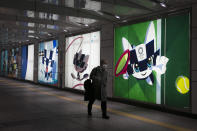 A man with a mask walks past large displays promoting the Tokyo 2020 Olympics Monday, Feb. 24, 2020, in Tokyo. (AP Photo/Jae C. Hong)