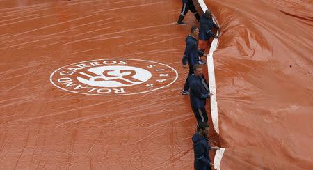 Tennis - French Open - Roland Garros - Paris, France - 23/05/16 Workers remove a tarpaulin from Philippe Chatrier court after the rain. REUTERS/Gonzalo Fuentes