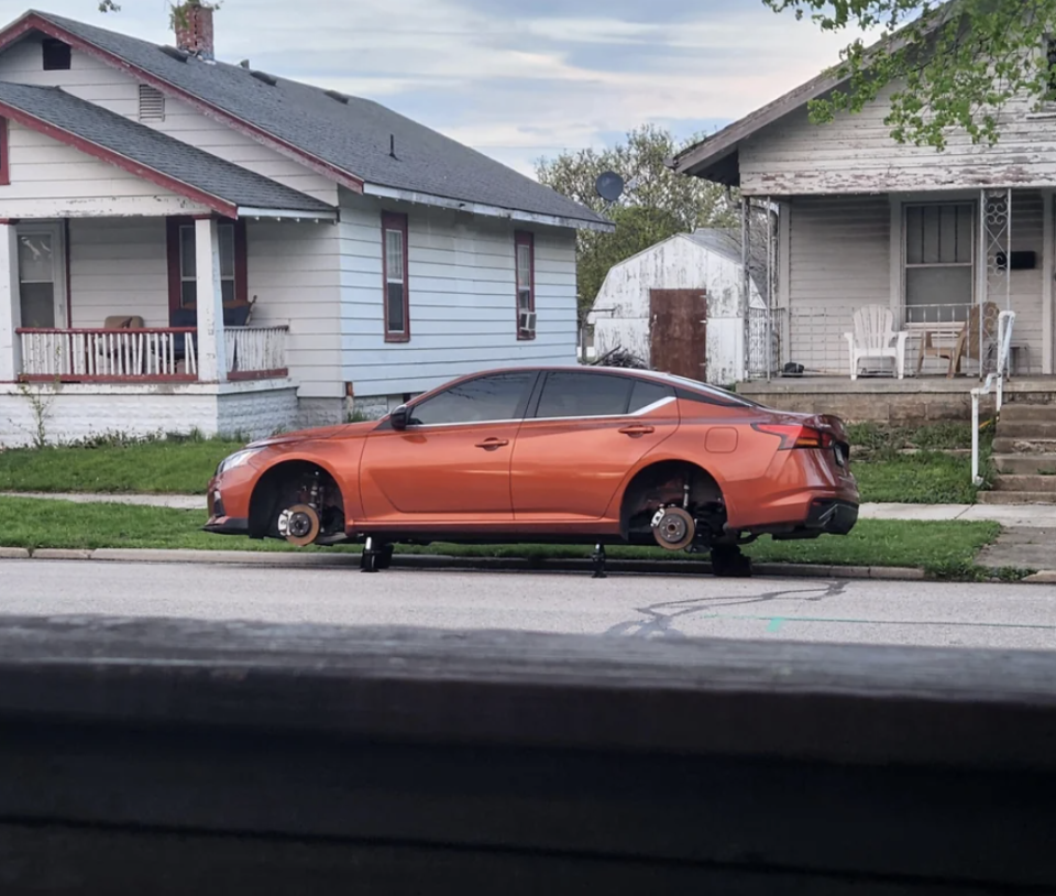 Car on jacks without wheels parked on a suburban street