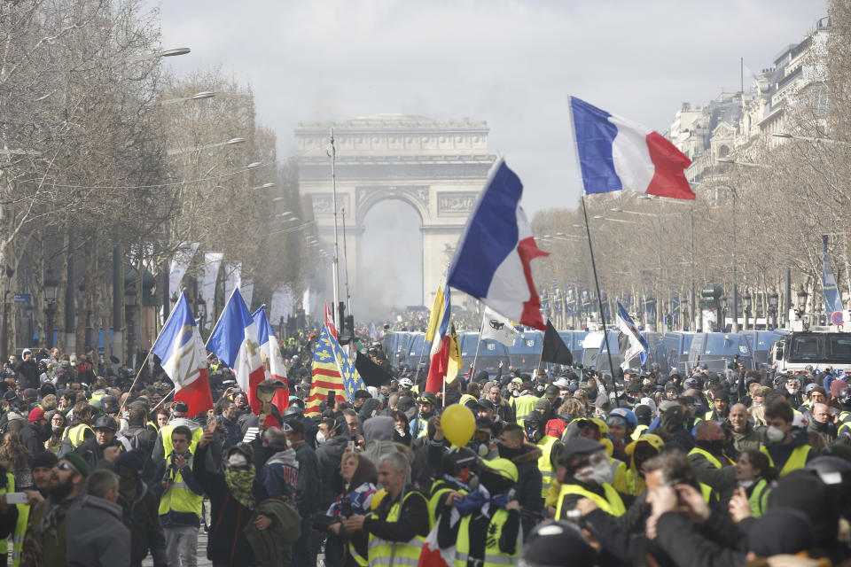 Yellow vests demonstrators invade the Champs Elysees avenue Saturday, March 16, 2019 in Paris. French yellow vest protesters clashed Saturday with riot police near the Arc de Triomphe as they kicked off their 18th straight weekend of demonstrations against President Emmanuel Macron. (AP Photo/Christophe Ena)