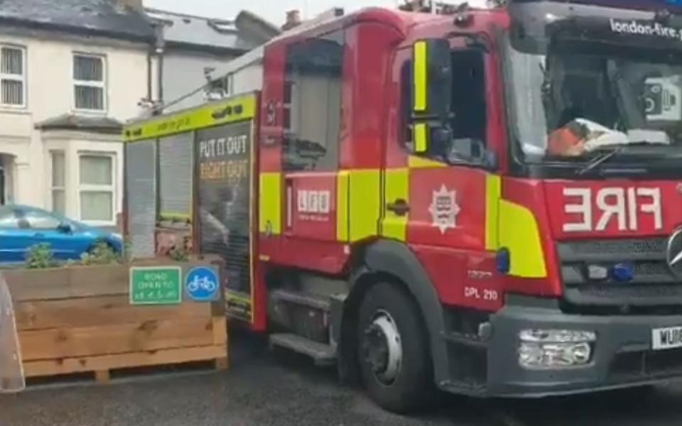 A fire engine stuck between a planter box and a parked car in Brixton - OneOval 