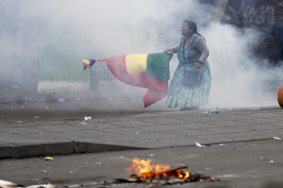 A supporter of former President Evo Morales holds a Bolivian flag during clashes with police in La Paz, Bolivia, Wednesday, Nov. 13, 2019. Bolivia's new interim president Jeanine Anez faces the challenge of stabilizing the nation and organizing national elections within three months at a time of political disputes that pushed Morales to fly off to self-exile in Mexico after 14 years in power. (AP Photo/Natacha Pisarenko)