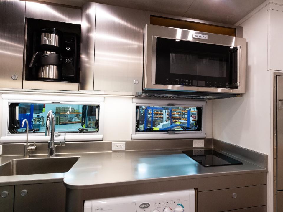 the kitchen with a countertop, sink, and microwave among two windows