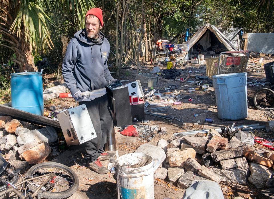 Tom Tom, one of the unhoused people living off Beggs Lane, tidies up his campsite near the Escambia Wood Superfund site off Palafox Street on Friday, Feb. 2, 2024.