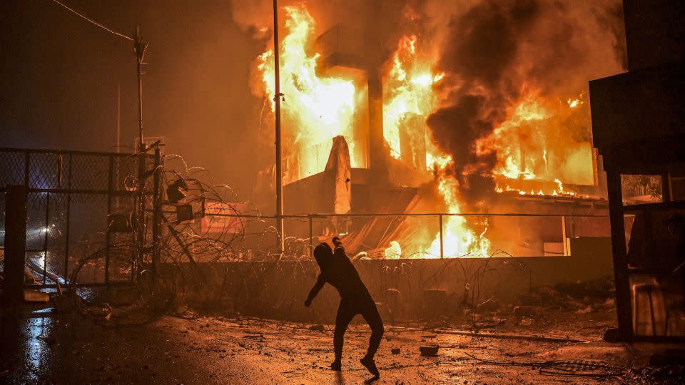 A Lebanese protester hurls stones at a burning building just outside the US Embassy in Beirut during a protest in solidarity with the people of Gaza on October 18. - Stringer/dpa/picture alliance/Getty Images