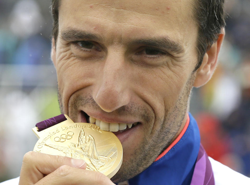 FILE - Tony Estanguet of France bites his Olympic gold medal after winning the final of the C-1 men's canoe slalom at Lee Valley Whitewater Center, at the 2012 Summer Olympics, Tuesday, July 31, 2012, in Waltham Cross near London. Estanguet who won gold medals for canoeing in the 2000, 2004 and 2012 Olympic Games is now the face and chief organizer of the 2024 Paris Games. In a wide-ranging interview with The Associated Press, Estanguet talks about the two French police probes into Olympic-related contracts, and insists they bear no comparison with corruption and ethics scandals that have dogged the Olympic movement and its flagship money-spinning event for decades. (AP Photo/Kirsty Wigglesworth, File)