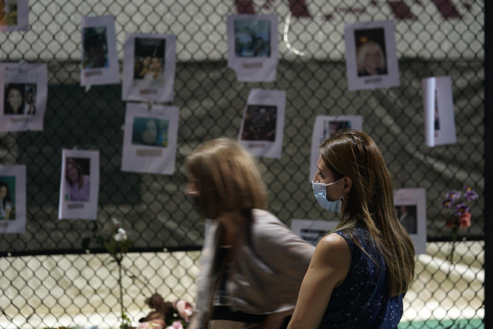 Angelica Pulido looks at a makeshift memorial with photos of some of the missing people near the site of an oceanfront condo building that partially collapsed in Surfside, Fla., Friday, June 25, 2021. (AP Photo/Gerald Herbert)