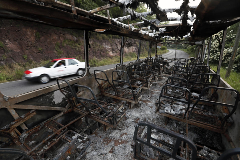 ARCHIVO - En esta imagen del 16 de octubre de 2019, autobuses quemados por miembros del crimen organizado en una carretera de doble sentido en El Aguaje, México. Un grupo de la policía estatal de Michoacán, Mëxico, hizo una inusual aparición en El Aguaje el lunes 14 de octubre de 2019 y fue emboscado y asesinado por hombres armados del cártel Jalisco Nueva Generación. (AP Foto / Marco Ugarte)