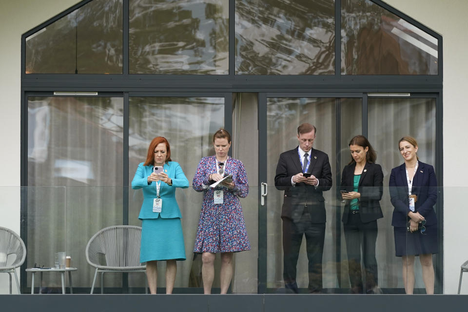 White House press secretary Jen Psaki, from left, White House communications manager Kate Bedingfield, national security adviser Jake Sullivan, Amanda Sloat, senior director for Europe on the National Security Council, and Yael Lempert, Chargé d'Affaires at the U.S. Embassy in London, stand on a balcony as President Joe Biden speaks about his administration's global COVID-19 vaccination efforts ahead of the G-7 summit, Thursday, June 10, 2021, in St. Ives, England. (AP Photo/Patrick Semansky)