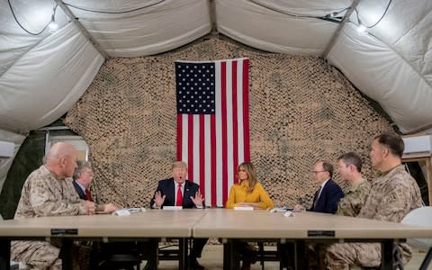 President Donald Trump, accompanied by National Security Adviser John Bolton, third from left, first lady Melania Trump, fourth from right, US Ambassador to Iraq Doug Silliman, third from right, and senior military leadership, speaks to members of the media at Al Asad Air Base, Iraq - Credit: AP Photo/Andrew Harnik