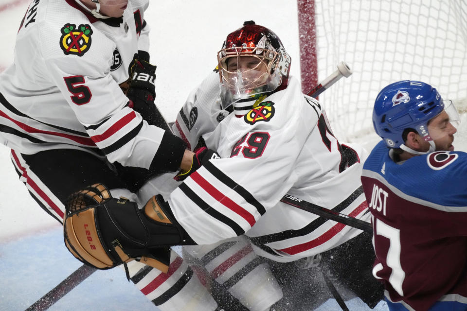 Chicago Blackhawks defenseman Connor Murphy, left, crashes into goaltender Marc-Andre Fleury after getting called for holding Colorado Avalanche left wing Tyson Jost on a breakaway shot during the second period of an NHL hockey game Wednesday, Oct. 13, 2021, in Denver. (AP Photo/David Zalubowski)