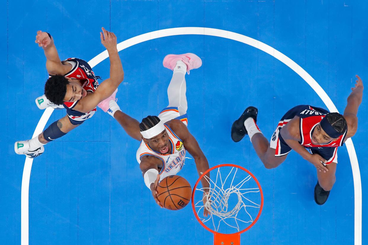 Oklahoma City Thunder guard Shai Gilgeous-Alexander (2) goes to the basket between Washington Wizards guard Jordan Poole, left, and guard Bilal Coulibaly (0) during an NBA basketball game between the Oklahoma City Thunder and the Washington Wizards at Paycom Center in Oklahoma City, Friday, Feb. 23, 2024.