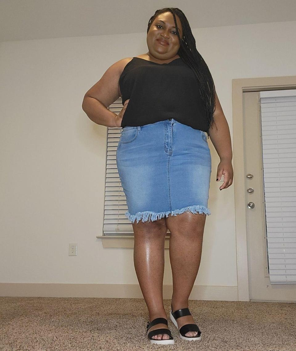 The writer wearing a black spaghett-strap top with a light-denim skirt that hits just above her knee and black chunky sandals