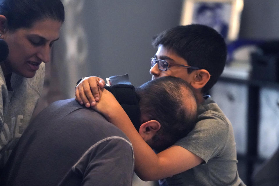 Ronan Kotiya, 11, right holds his father Rupesh Kotiya's head as his wife Siobhan Pandya, left, prepare to move him to bed at their home in Plano, Texas, Friday, April 8, 2022. Millions of Americans with serious health problems depend on children ages 18 and younger to provide some or all of their care at home. An exact number is hard to pin down, but researchers think millions of children are involved in caregiving in the U.S. (AP Photo/LM Otero)