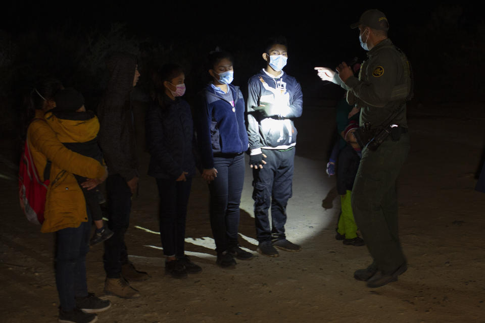 FILE - In this March 28, 2021 file photo Migrants from Guatemala and Honduras are questioned by a Border Patrol agent after being smuggled on an inflatable raft in Roma, Texas. The Biden administration says families arriving at the U.S. border with Mexico will have their cases fast-tracked in immigration court, an announcement on Friday, May 28, that comes less than two weeks after said it was easing pandemic-related restrictions on seeking asylum. Under the plan, immigration judges in 10 cities will aim to decide cases within 300 days. (AP Photo/Dario Lopez-Mills, File)