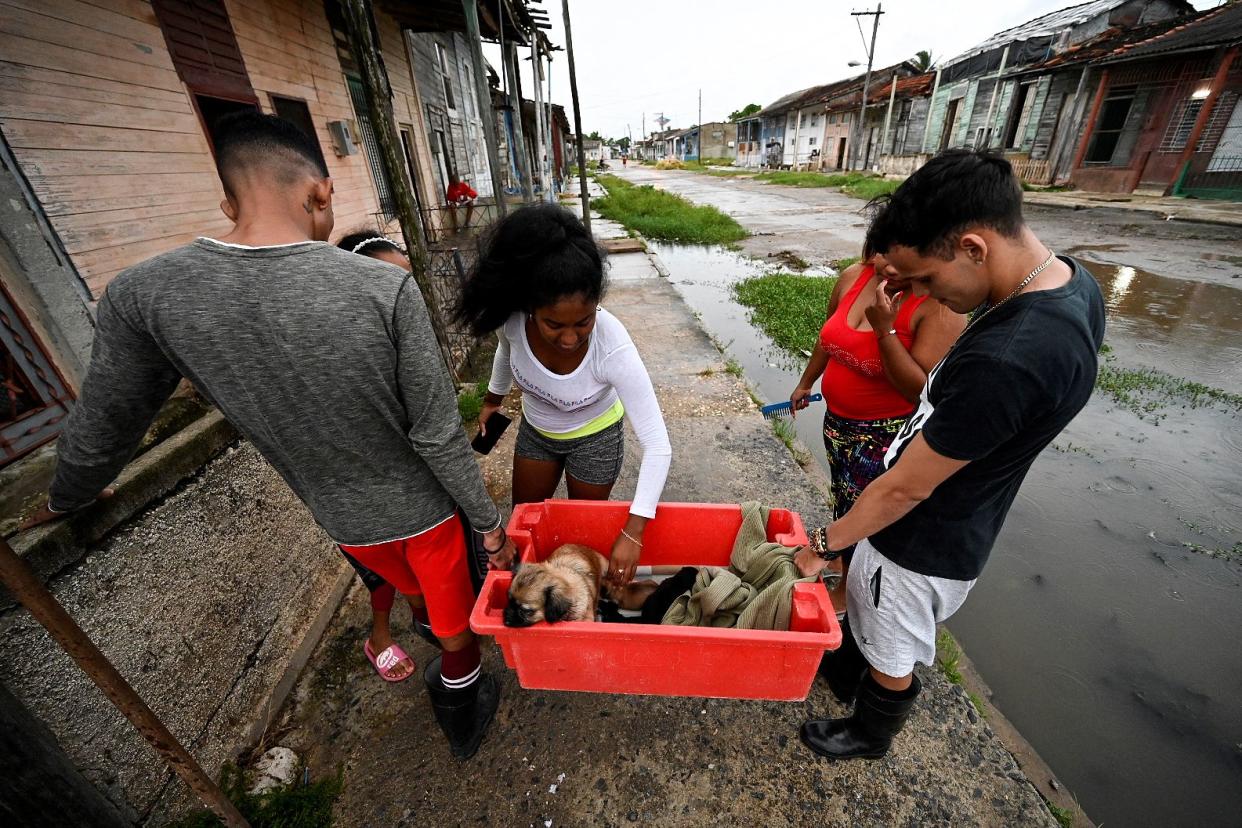 A family carries a dog to a safe place in Batabano, Mayabeque province, on Sept. 26, 2022, ahead of the arrival of Hurricane Ian in Cuba.